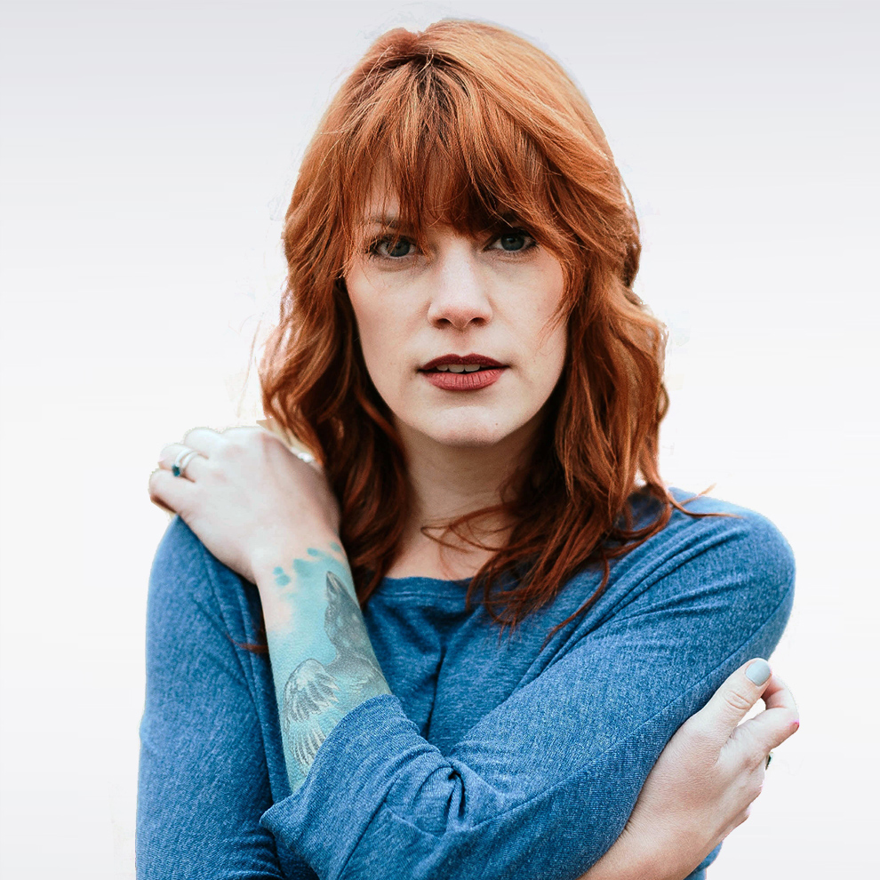 Portrait of a red-haired woman with blue eyes wearing a blue sweater.