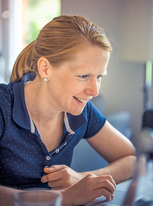 Smiling woman engaged in conversation, wearing a navy blue shirt.