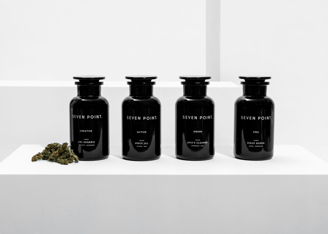 Four black apothecary jars with labels on a white surface.