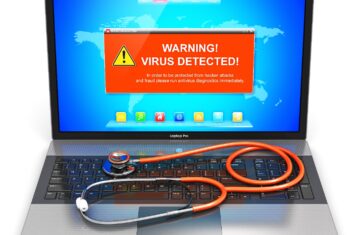 Laptop with virus warning and a stethoscope on keyboard.
