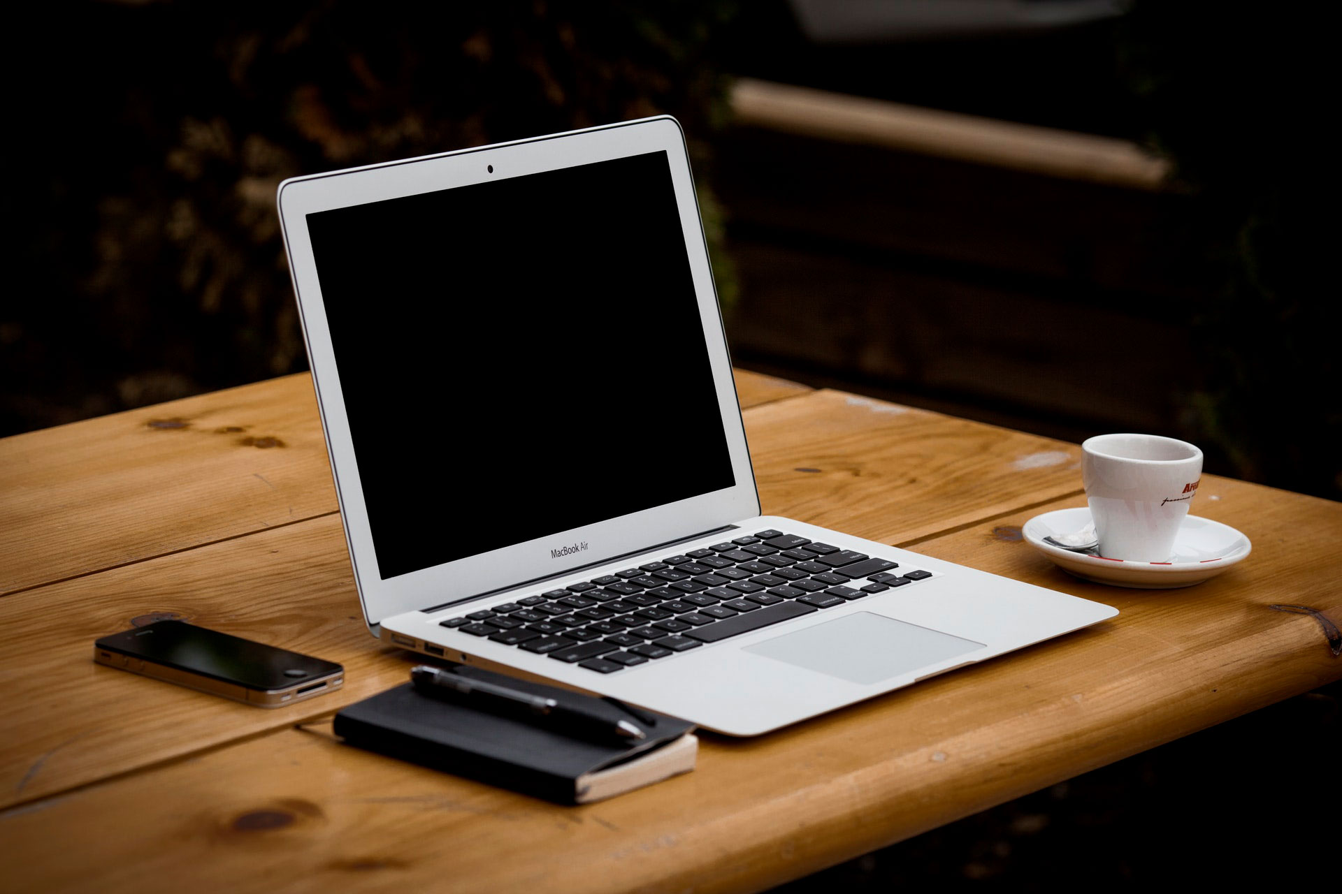 Laptop with coffee, notebook, and phone.